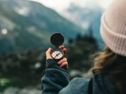 Woman hiking, holding a compass in her hand