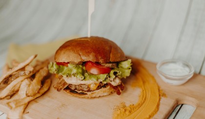tasty burger on a board with chips and sour cream on the side