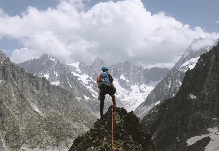 Climber standing on the top of the mountain looking out into the valley